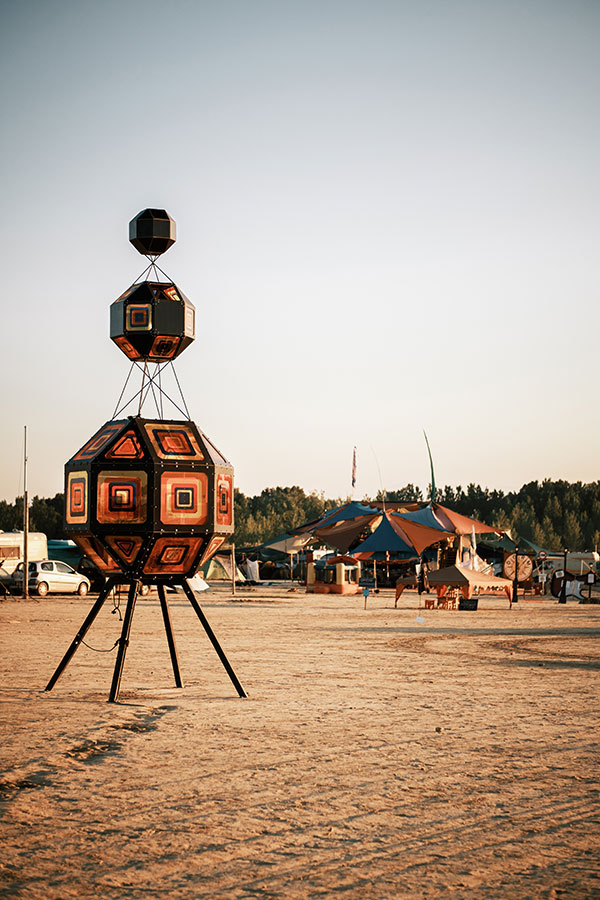 Geometric shapes with orange patterns standing on metal legs beside a Nowhere camp