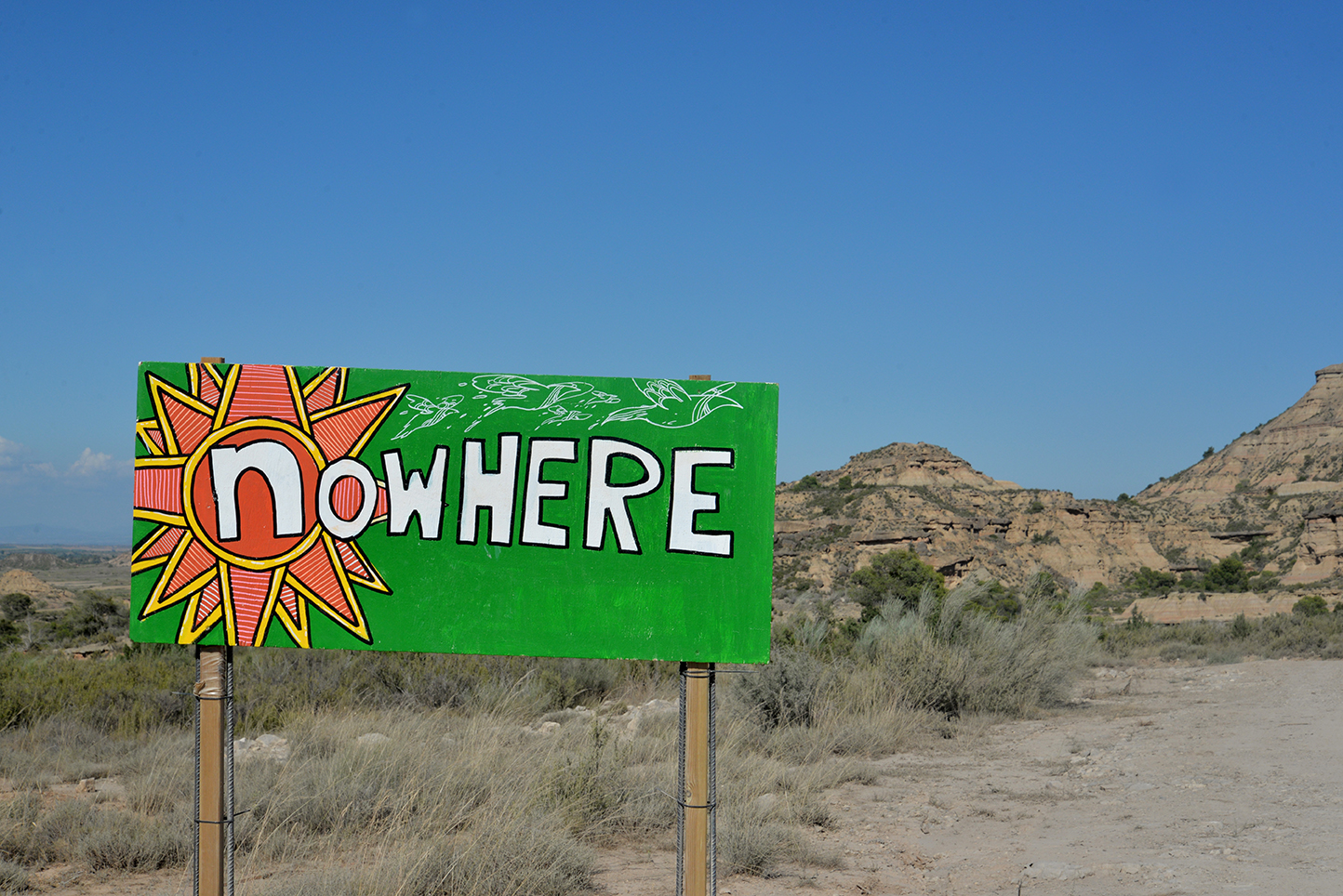 Green hand-painted Nowhere sign in a dry, rocky landscape