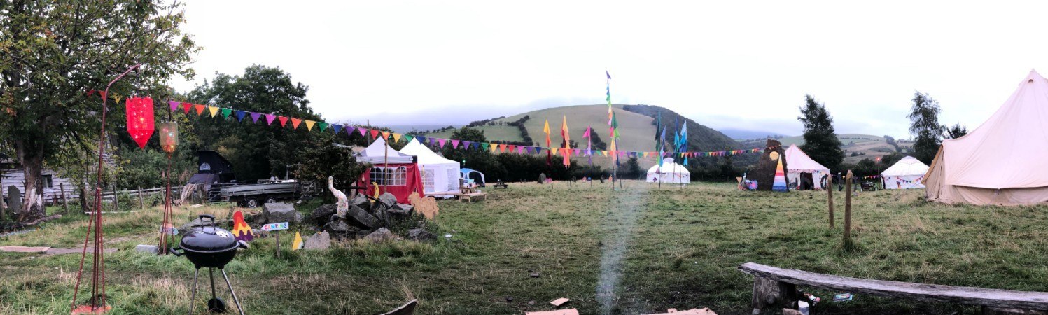 Colourful bunting and camp tents at MicroBurn in 2019, with Welsh hills behind the site.