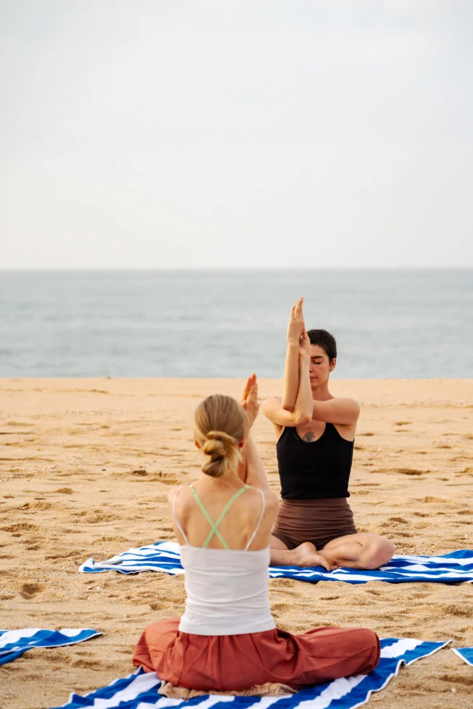 Two people practising seated yoga on Rekawa Beach.